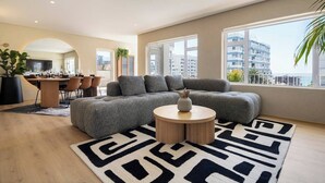 A modern living room with a sectional sofa, a round coffee table, and a patterned rug. - Magic on Main (Cape Town)