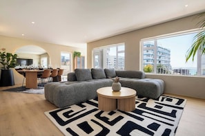A modern living room with a sectional sofa, a round coffee table, and a patterned rug. - Magic on Main (Cape Town)