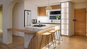 A modern kitchen with a central island, bar stools, wooden cabinets, and a pendant light. - Magic on Main (Cape Town)