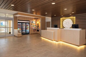 A reception area with a counter, a refrigerator stocked with beverages, and a decorative wall piece.