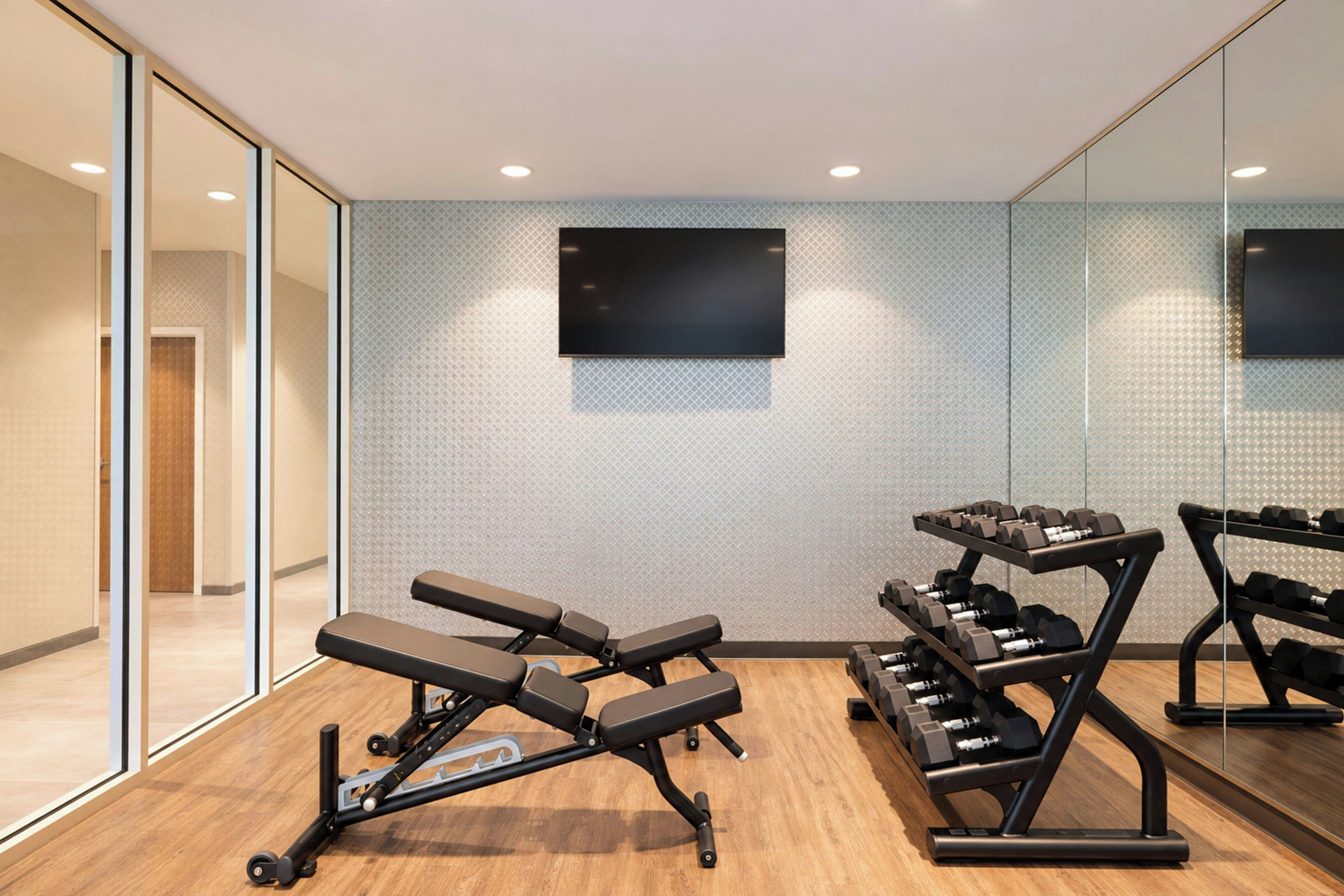 Een moderne sportschool met een bank, halters en een televisie aan de muur.