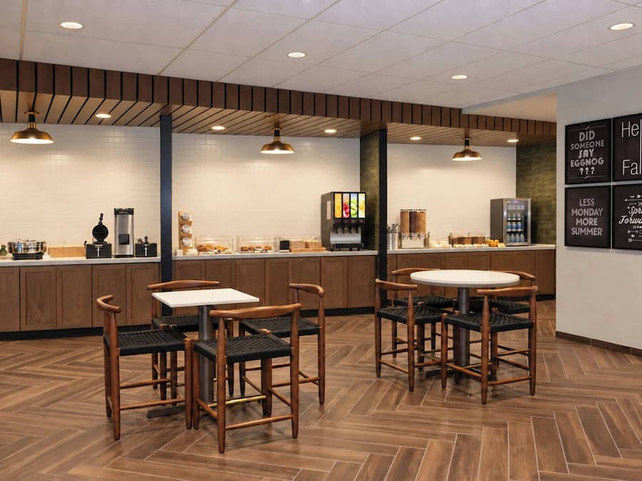 A modern cafe interior with wooden flooring, a central counter, and seating area.