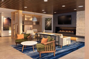A modern living room with a fireplace, seating area, and a television mounted on the wall.