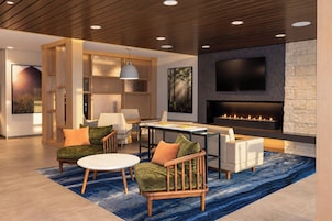 A modern living room with a fireplace, seating area, and a television mounted on the wall.