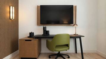 A modern office space with a wooden desk, a green office chair, a black monitor, and a lamp.