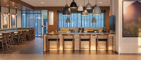 A modern kitchen with a central island, bar seating, and pendant lighting.