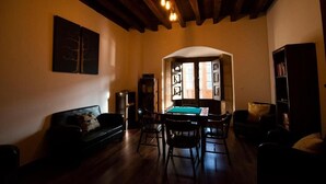 Una sala de estar con mesa de billar, vigas de madera en el techo y una estantería.