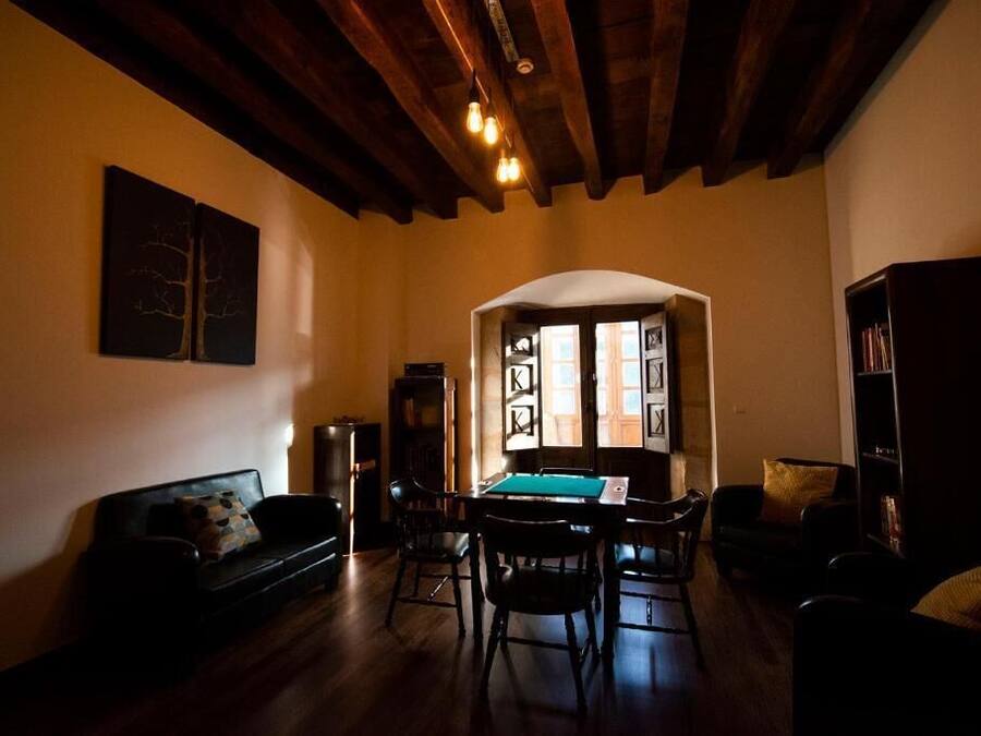 Una sala de estar con mesa de billar, vigas de madera en el techo y una estantería.