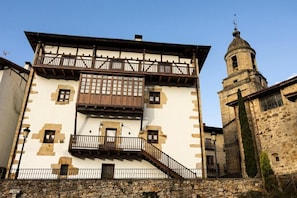 Un edificio histórico con balcón, pared de piedra y torre.