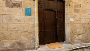 Un edificio de piedra con una puerta de madera grande, un letrero que dice 'Soran' y un letrero azul con la letra 'H'.