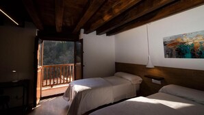 Una habitación con dos camas, techo de madera, un cuadro en la pared y un balcón con vistas.