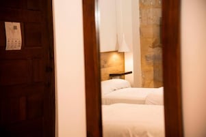 Un dormitorio con dos camas, una puerta de madera y una pared de piedra.