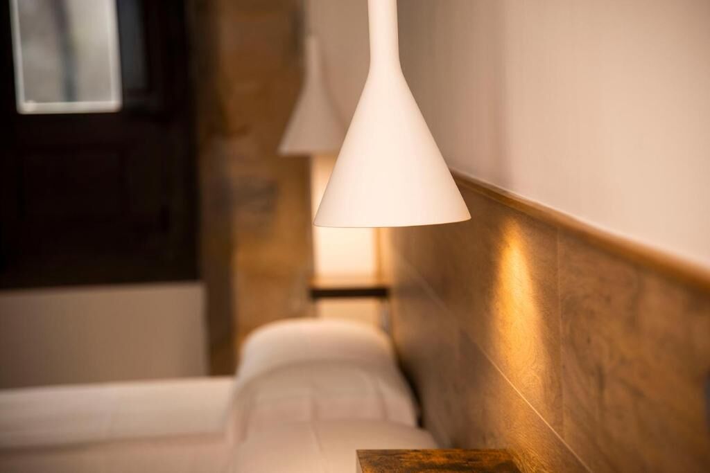 Ein Hotelzimmer mit einem Bett, einem hölzernen Kopfteil und einer Pendelleuchte.