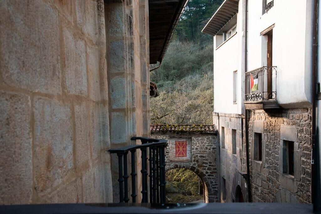 A stone building with a balcony, a stone archway, and a flag.