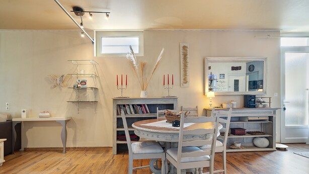 Un coin repas avec une table ronde, des chaises blanches, une bibliothèque et un miroir.