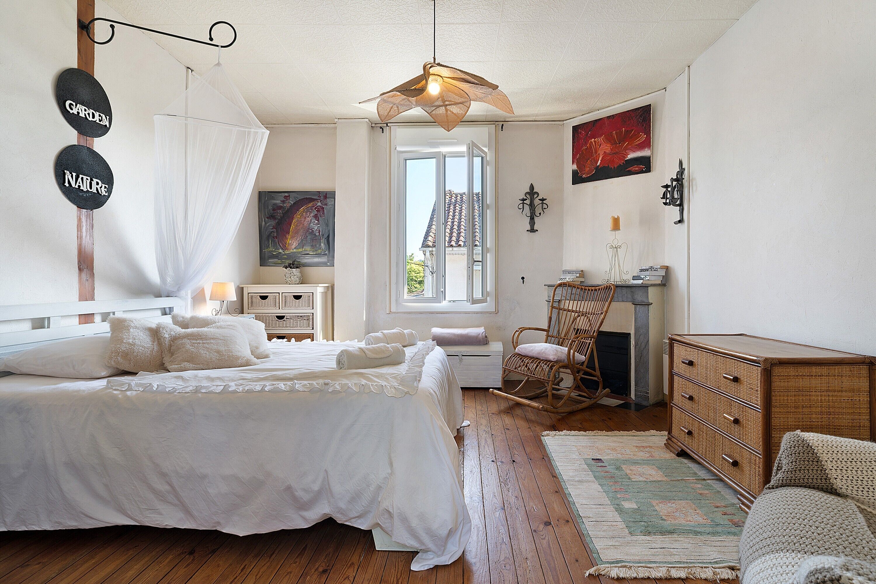 Une chambre à coucher avec un lit, une chaise, une commode et une fenêtre donnant sur un paysage agréable.