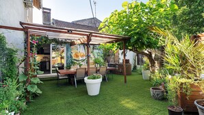 Une terrasse dotée d’une pergola, une table à manger avec des chaises et des plantes en pot.