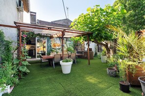 Een terras met een pergola, een eettafel met stoelen en potplanten.
