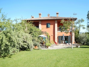 A two-story house with a tiled roof, a balcony, and a garden area with outdoor furniture. - Farmhouse with garden, parking and fitness area near Bologna center (Bologna, Emilia-Romagna)