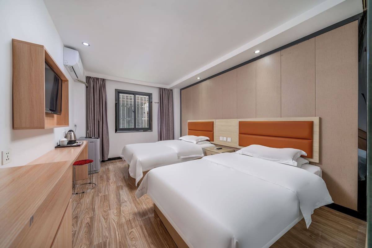 Una habitación de hotel con dos camas, un escritorio, un televisor y una ventana.