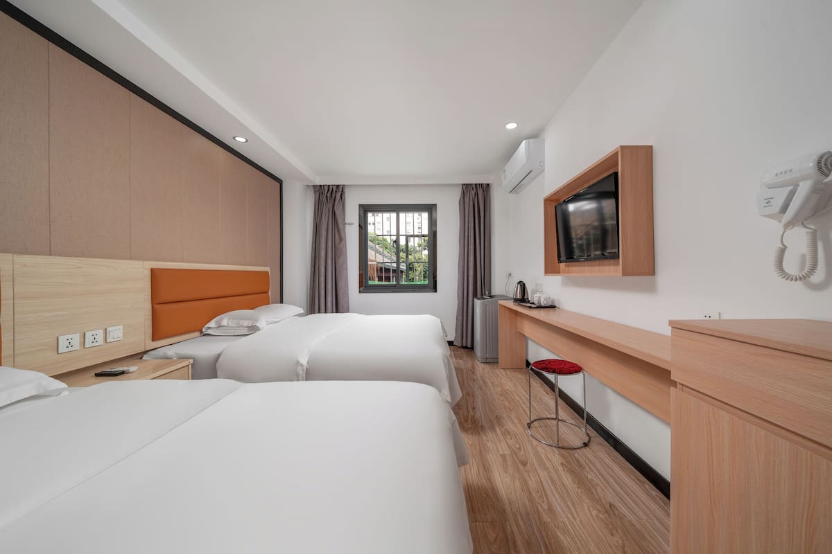 Habitación de hotel con dos camas, un escritorio, un espejo, un televisor y un secador de pelo.