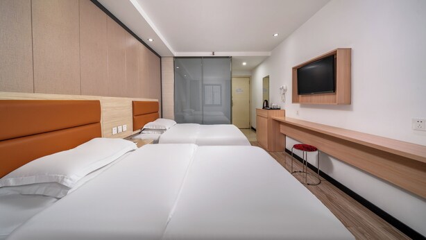 Habitación de hotel con dos camas, televisor, escritorio y espejo.