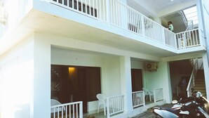 A multi-story building with balconies, a staircase, and a parked motorcycle. - Bougain villa (Canacona)