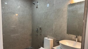A bathroom with a toilet, a sink, and a shower. - Bougain villa (Canacona)