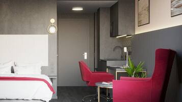 A modern hotel room with a bed, two red chairs, a desk, and a plant.