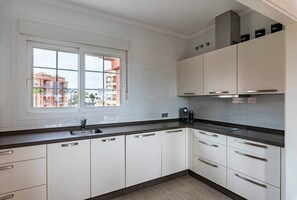 A modern kitchen with white cabinetry, a black countertop, and a window with a view of buildings. - Casa Arte-Luxury Apartments Islantilla-RuitenAppartementen (Lepe)