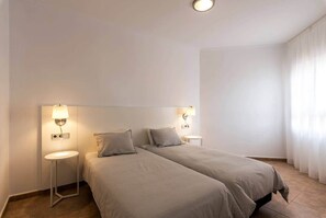 A hotel room with two beds, bedside tables, and wall-mounted lamps. - Casa Mar-Luxury Apartments Islantilla-RuitenAppartementen (Lepe)