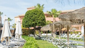 Un complexe hôtelier doté de chaises longues, de parasols et d’une pelouse bien entretenue.