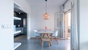 Une cuisine moderne dotée d’un four encastré, un coin repas avec une table et des chaises, et une grande porte-fenêtre coulissante donnant sur un espace extérieur.