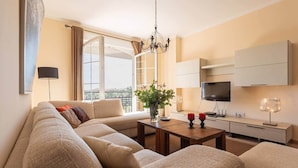 A modern living room with a sofa, coffee table, TV, and a plant.