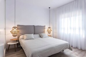 Ein modernes Schlafzimmer mit einem großen Bett, zwei Nachttischen und einer Hängelampe.