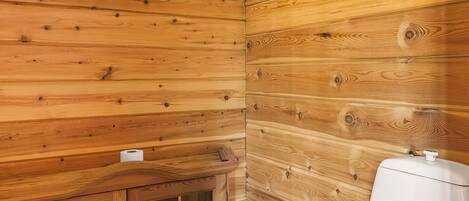 Un baño con paneles de madera, un inodoro y un armario con puertas de cristal.