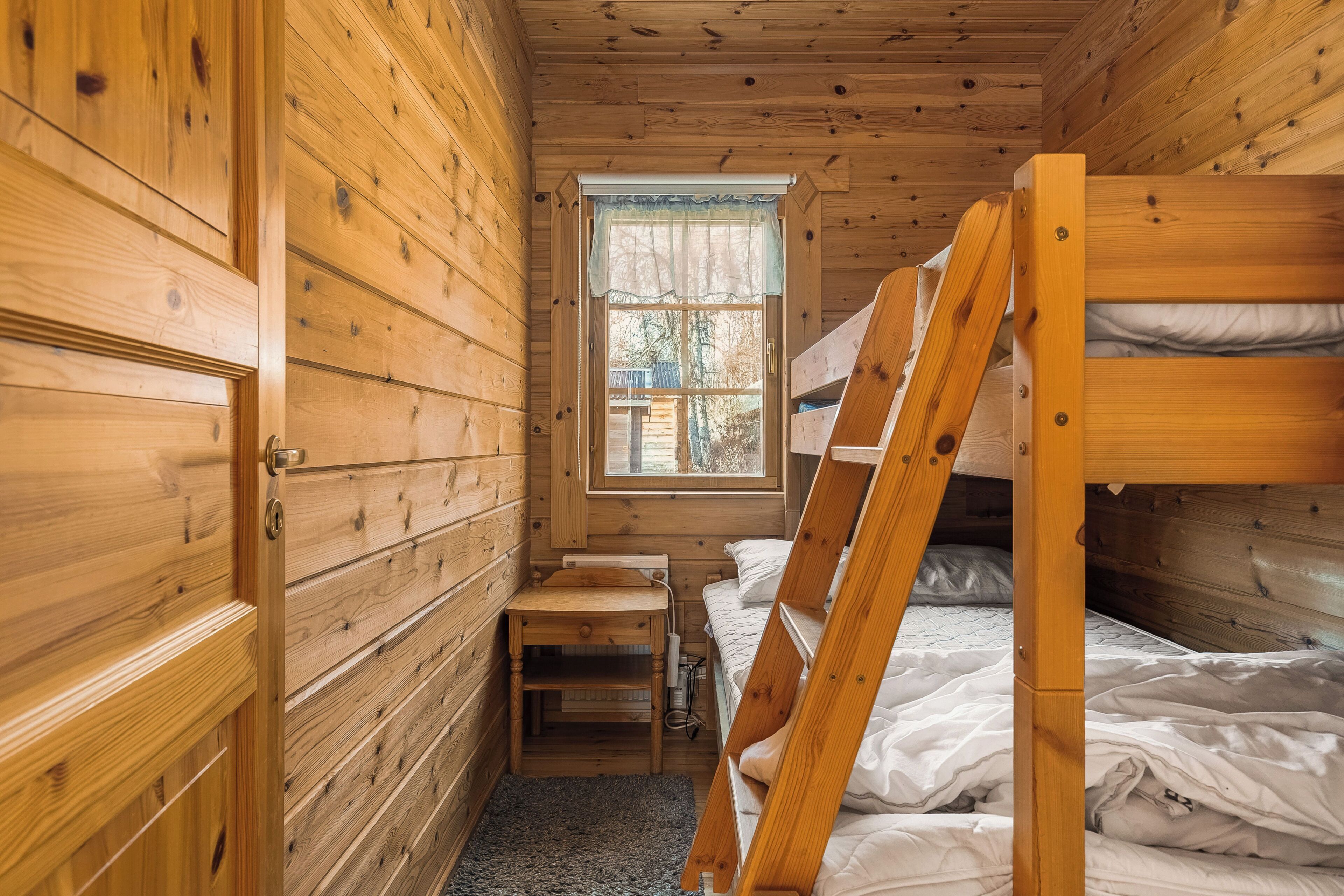 Ein Holzblockhauszimmer mit Stockbetten, einem Schreibtisch und einem Fenster.