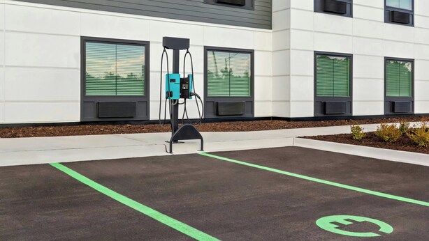 A parking area with electric vehicle charging stations, a building with large windows, and a clear sky. - StudioRes by Marriott Wilmington (Wilmington)