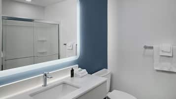 A modern bathroom with a large mirror, a sink, and a toilet.