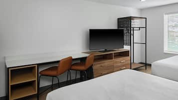 A modern hotel room with a desk, two chairs, a TV, a wardrobe, and two beds.