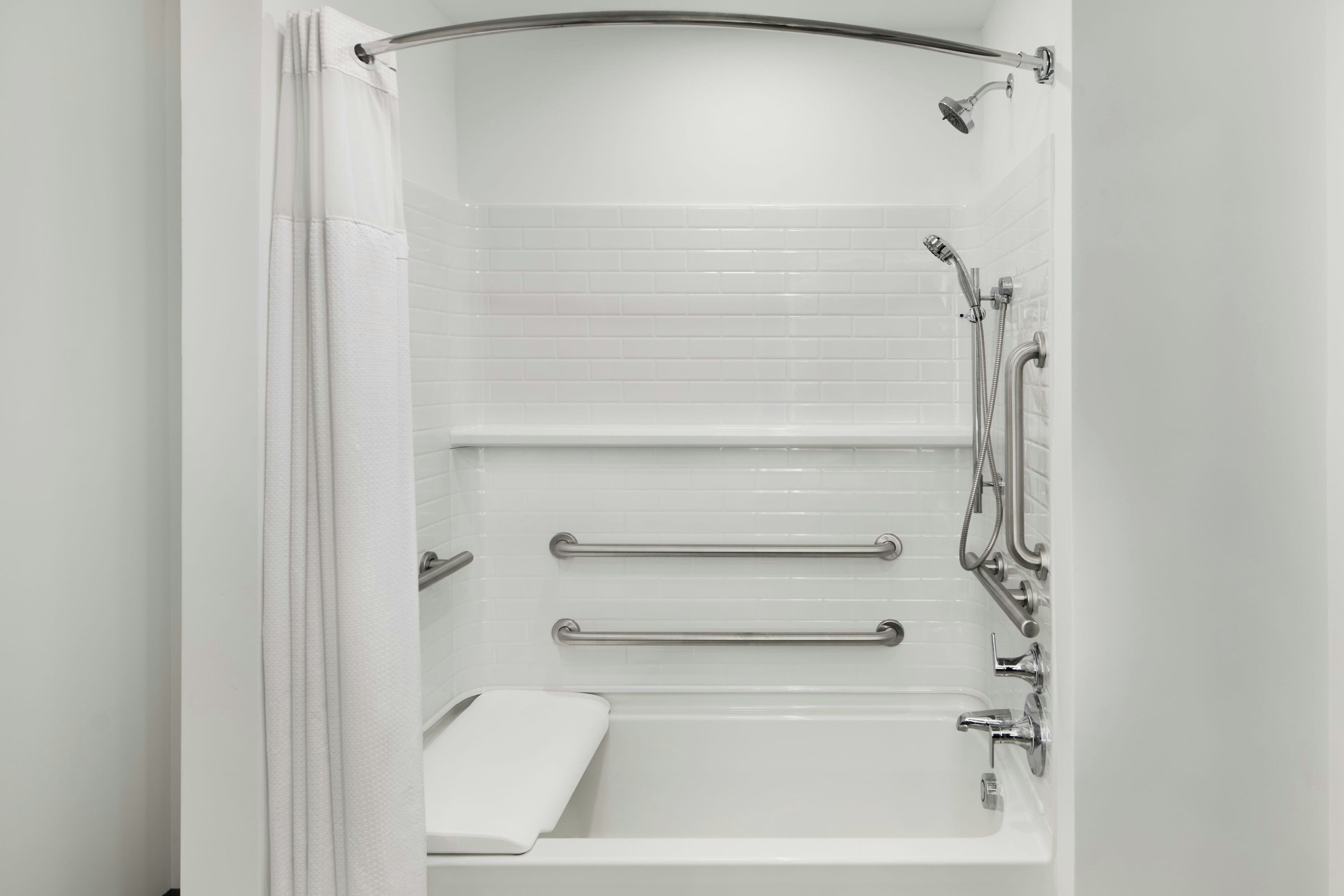A modern bathroom with a walk-in shower, grab bars, and a white bathtub.