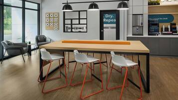 A modern kitchen with a coffee station, a seating area with chairs, and a large window.