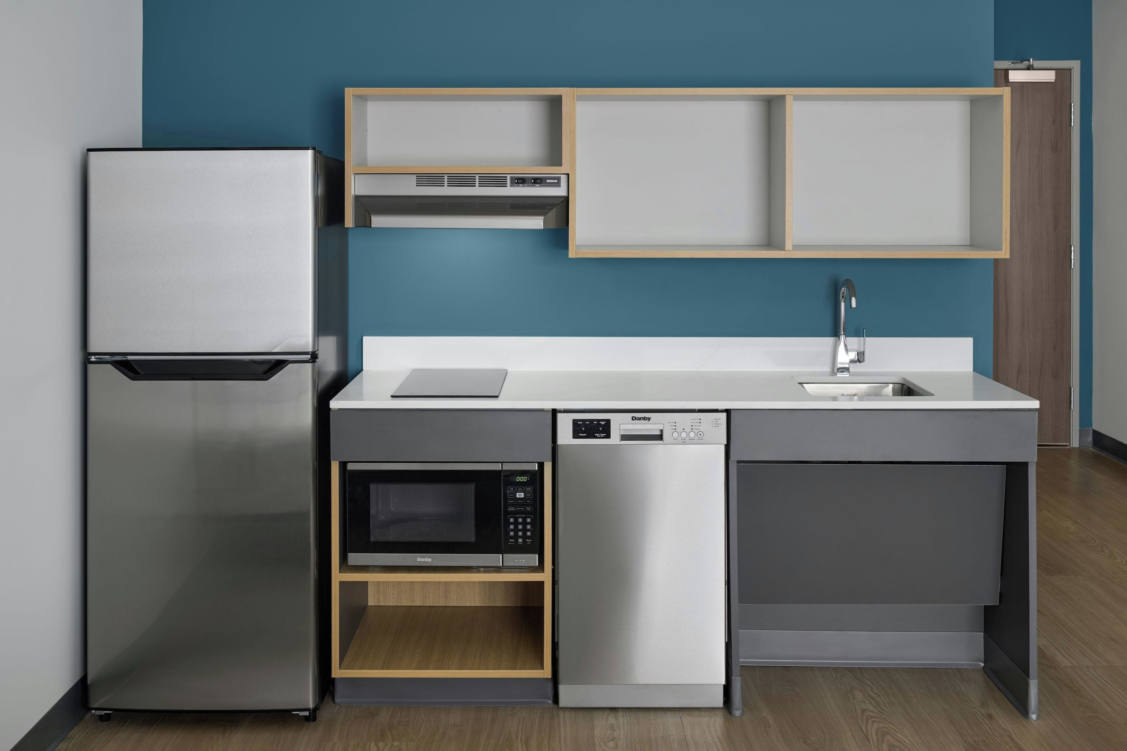 Una cocina moderna con refrigerador, microondas, lavavajillas y un lavamanos.