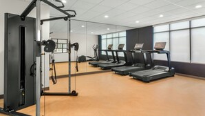 A gym with exercise equipment, treadmills, and a mirrored wall. - StudioRes by Marriott Wilmington (Wilmington)