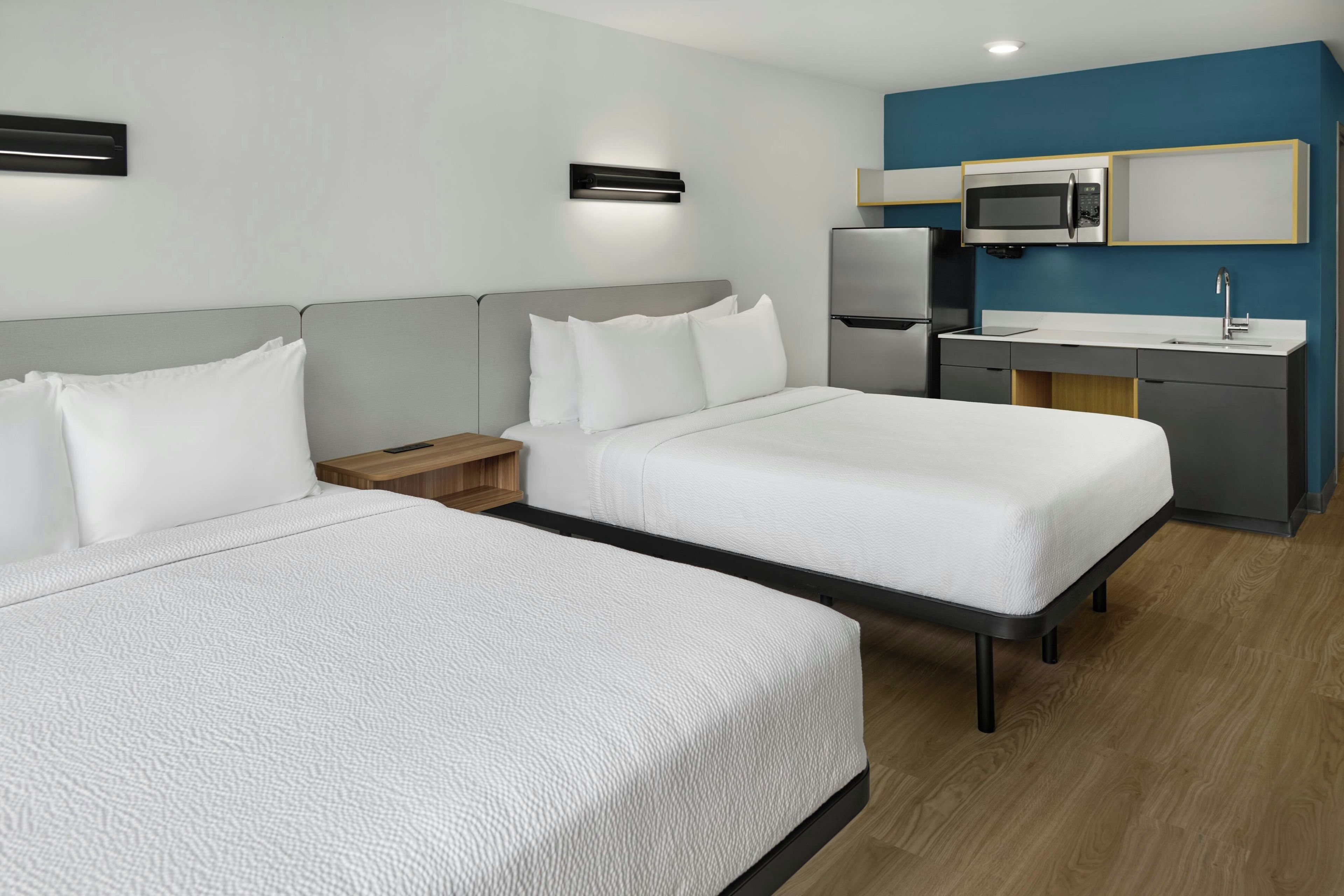 Habitación de hotel con dos camas, un escritorio, un microondas y un lavabo.