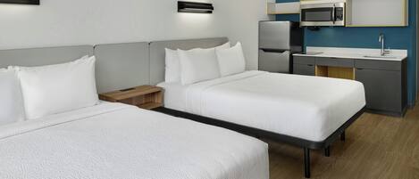 Habitación de hotel con dos camas, un escritorio, un microondas y un lavabo.