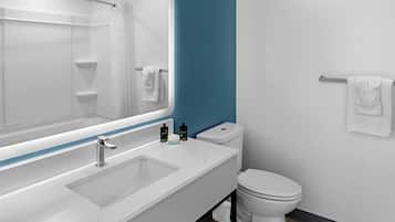 Une salle de bain moderne avec un lavabo blanc, un miroir, des toilettes et un porte-serviettes.