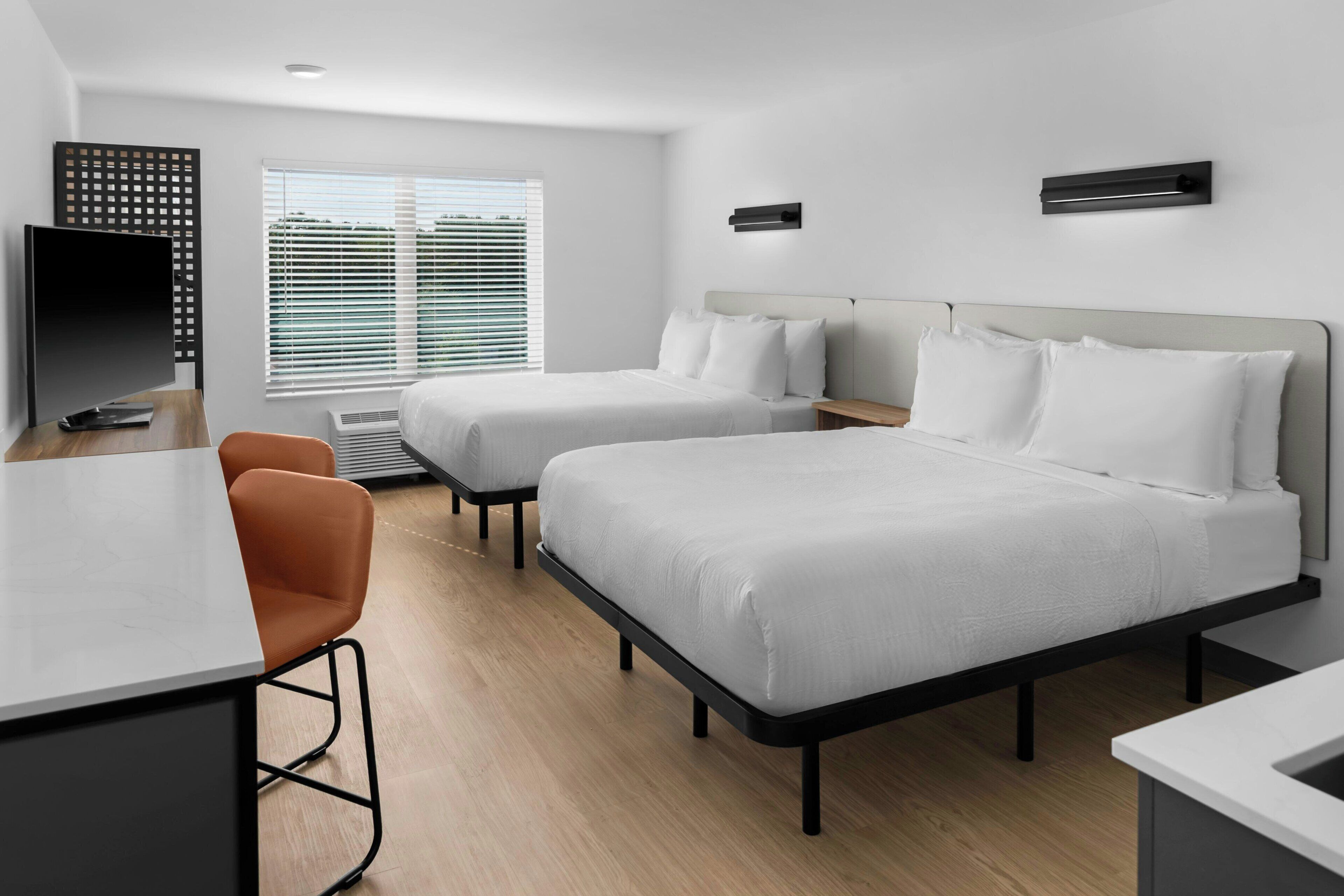 Une chambre d’hôtel moderne avec deux lits, un bureau et une chaise.
