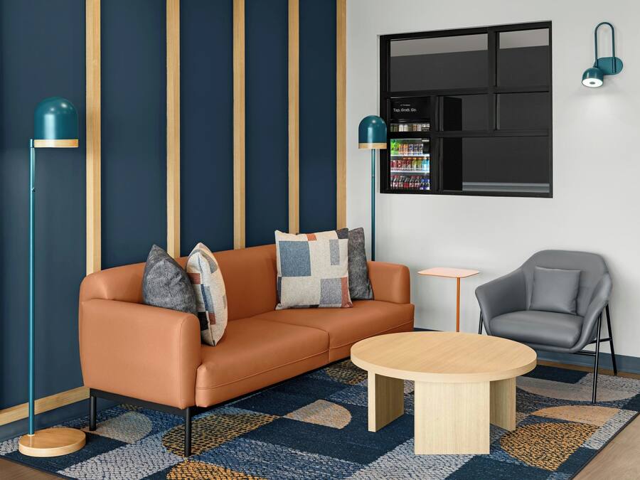 Un salon moderne comprenant un canapé, une table basse, un fauteuil, une lampe sur pied et un téléviseur fixé au mur.