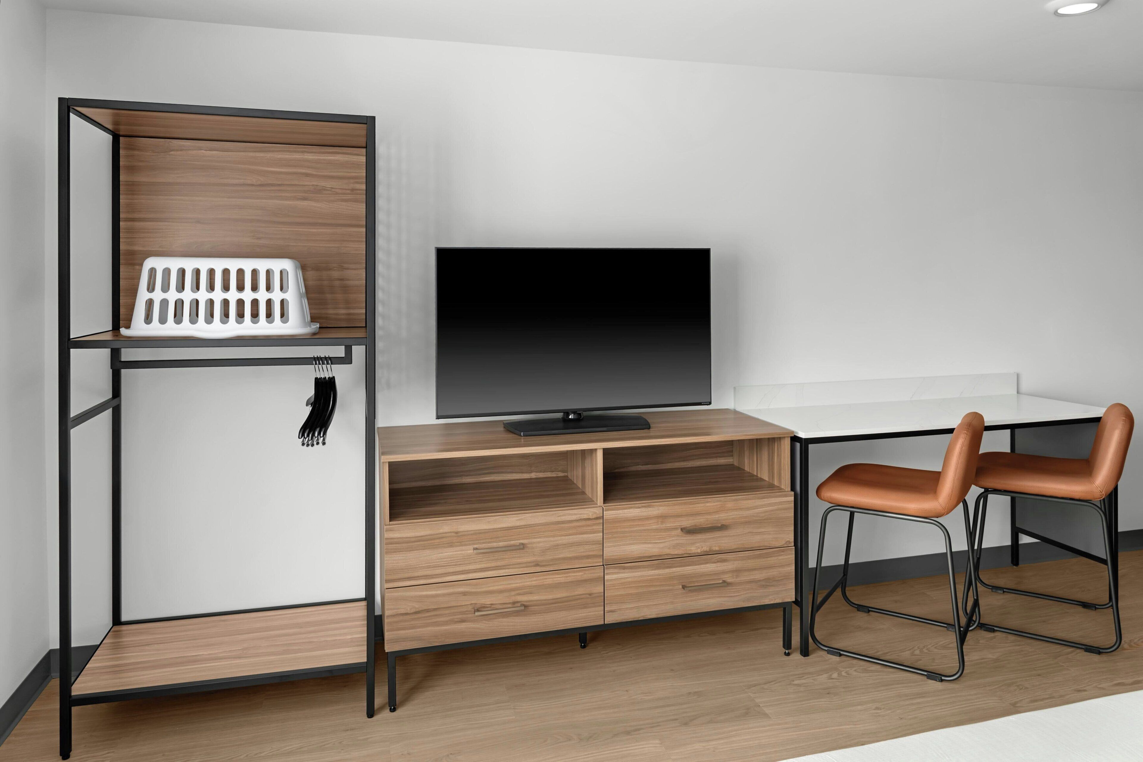 A modern room with a TV, a wooden cabinet, a desk, and two chairs.
